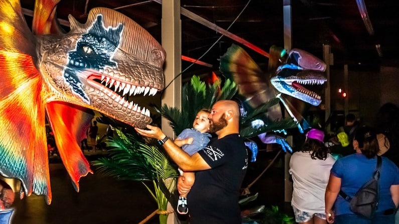 Father and son petting dinosaur for things to do this weekend in Austin.