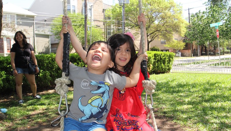 Kids laughing on the swing set for the embroidery event. 